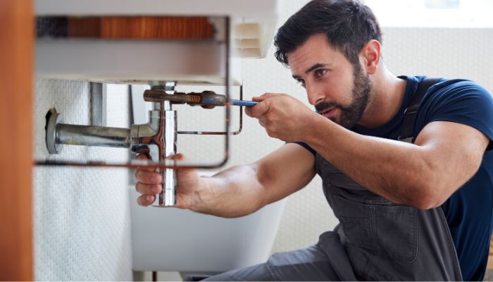 plumber fixing a drain pipe under a kitchen sink - Elizabeth Drain and Plumbing Services | Elizabeth, NJ
